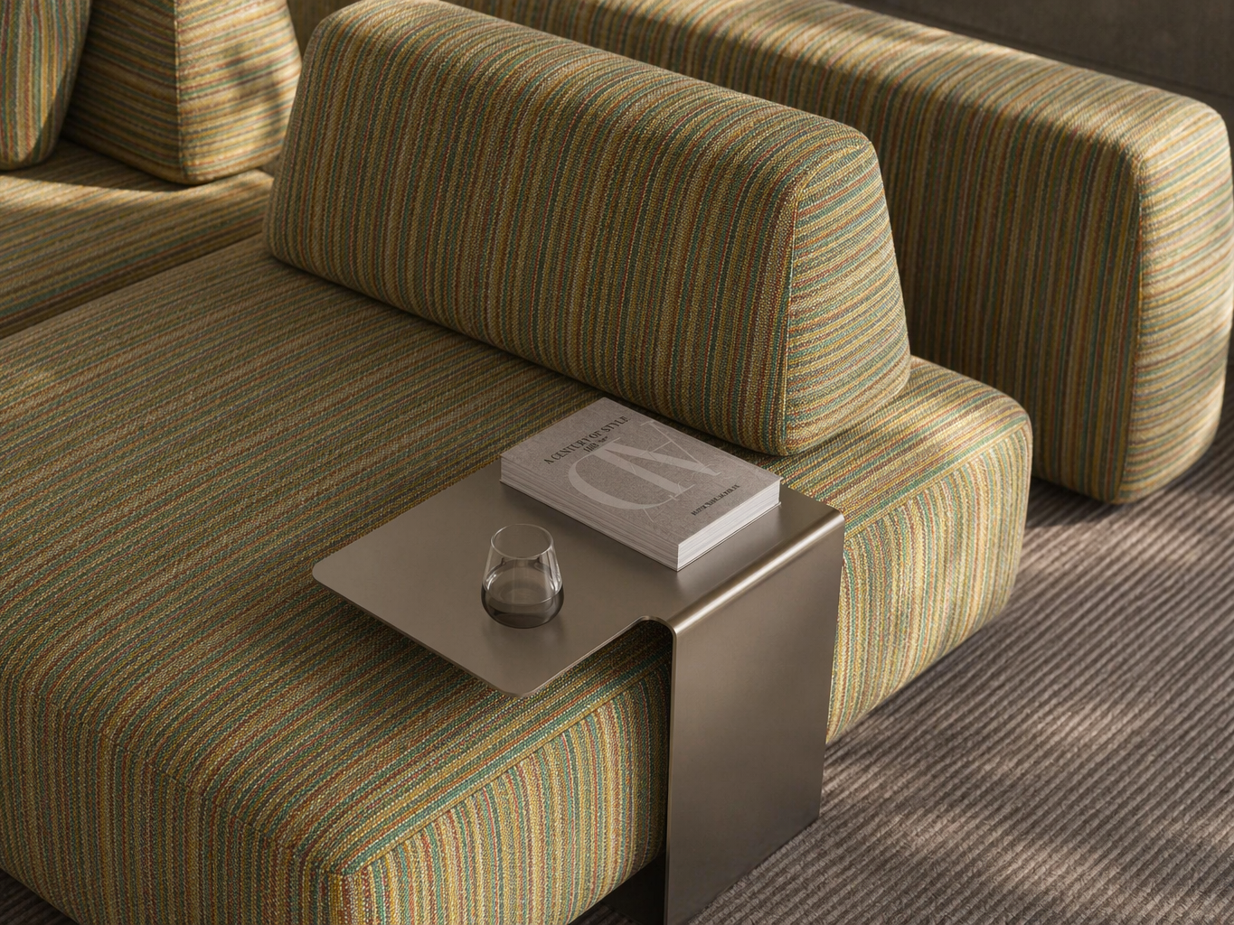 Modern modular sofa with textured multicolour striped upholstery, angled cushions, and a sleek metal side table in a refined living room setting - Beautiful Homes