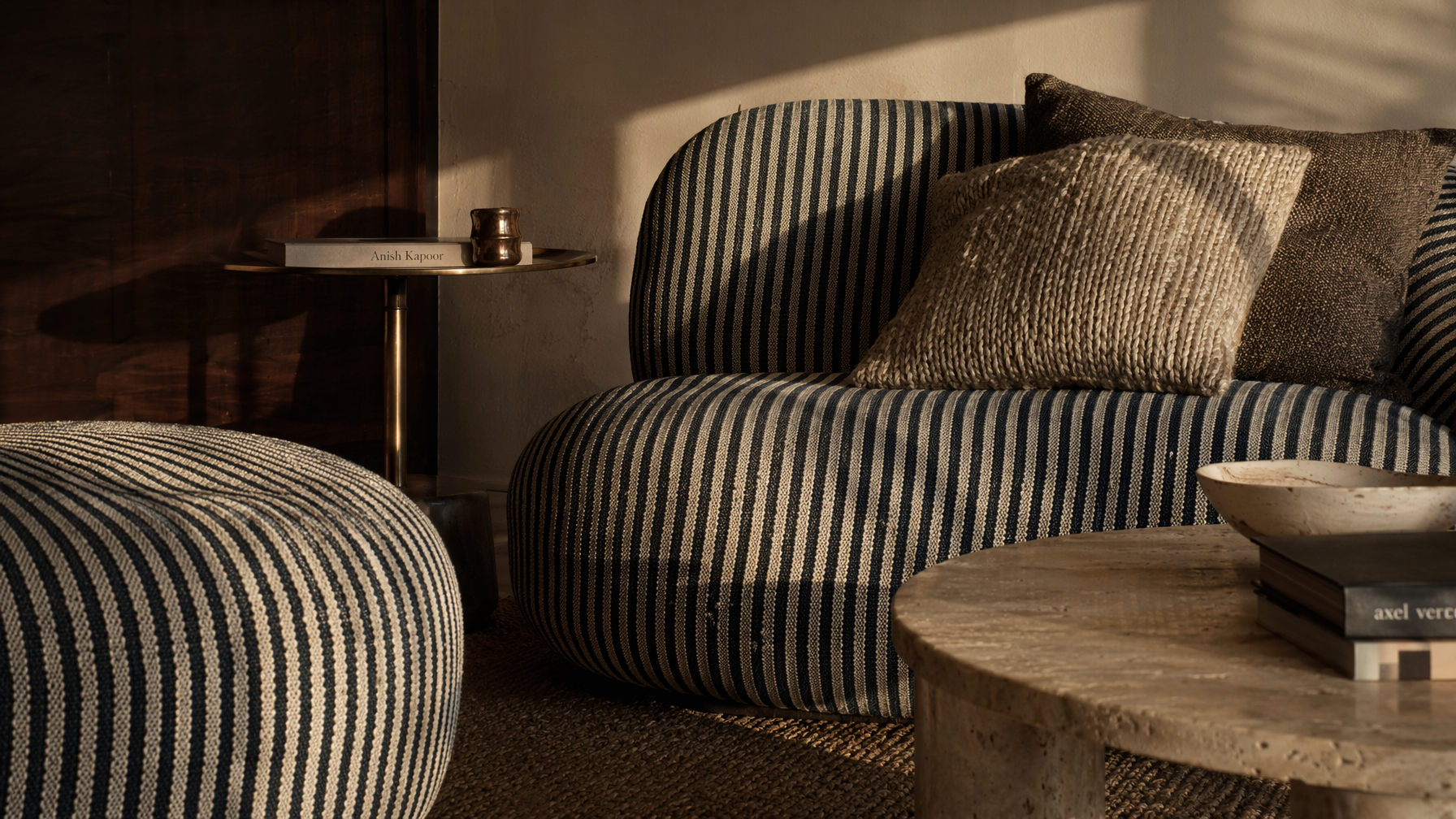 Low-profile sofa furnishing with black and cream striped upholstery, plush layered cushions, and a matching ottoman - Beautiful Homes