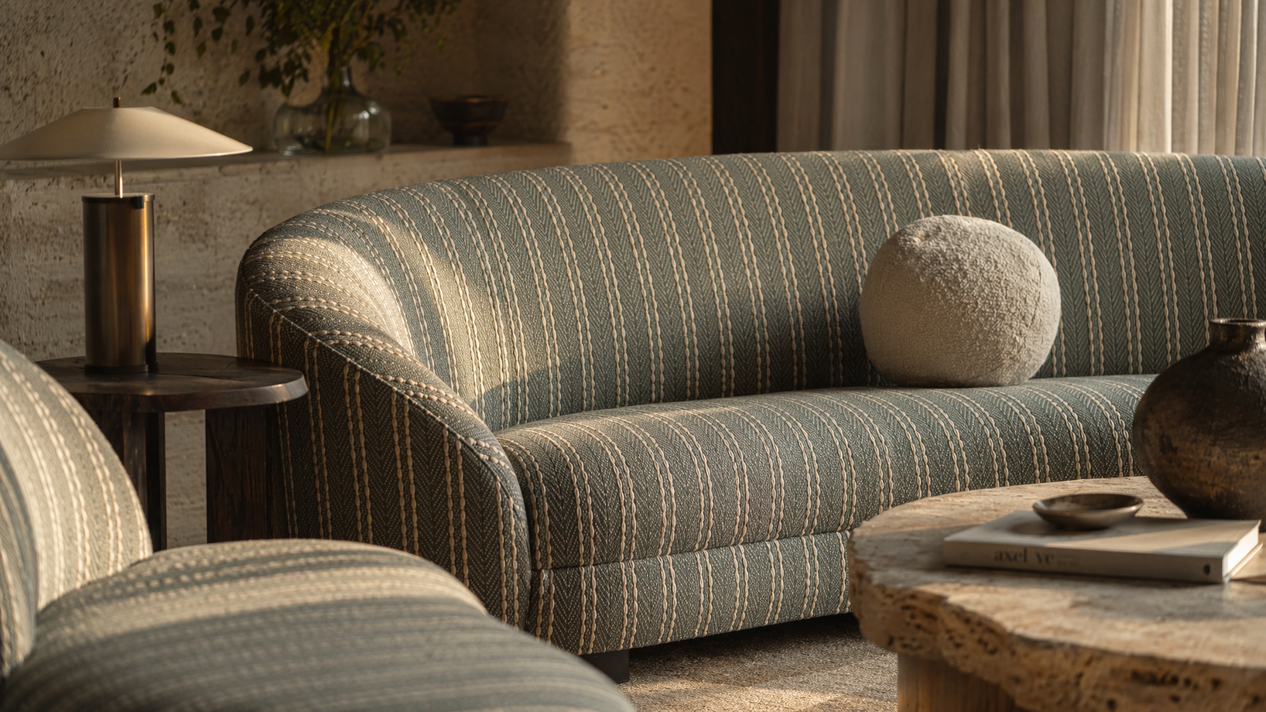 Curved sofa furnishing with muted green and beige striped upholstery, rounded backrest, and sculptural form - Beautiful Homes