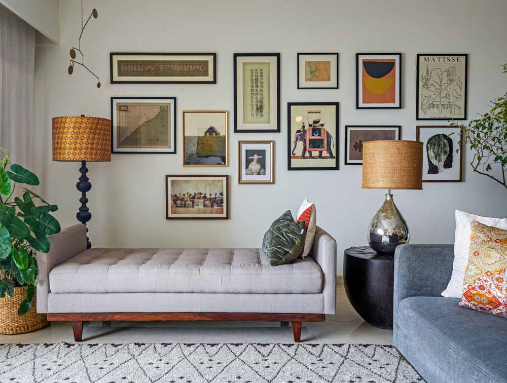 A gallery wall filled with frames and in front of it is. agrey bench - Beautiful Homes