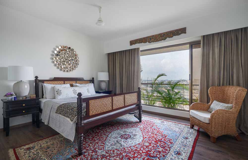 A bedroom with a large rug, a wooden bed in dark wood and two bedside tables - Beautiful Homes