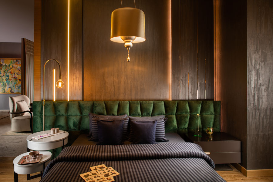 Round and White Bedroom Bedside Table Design With Green Velvet Headboard and Dark Coloured Bed - Beautiful Homes